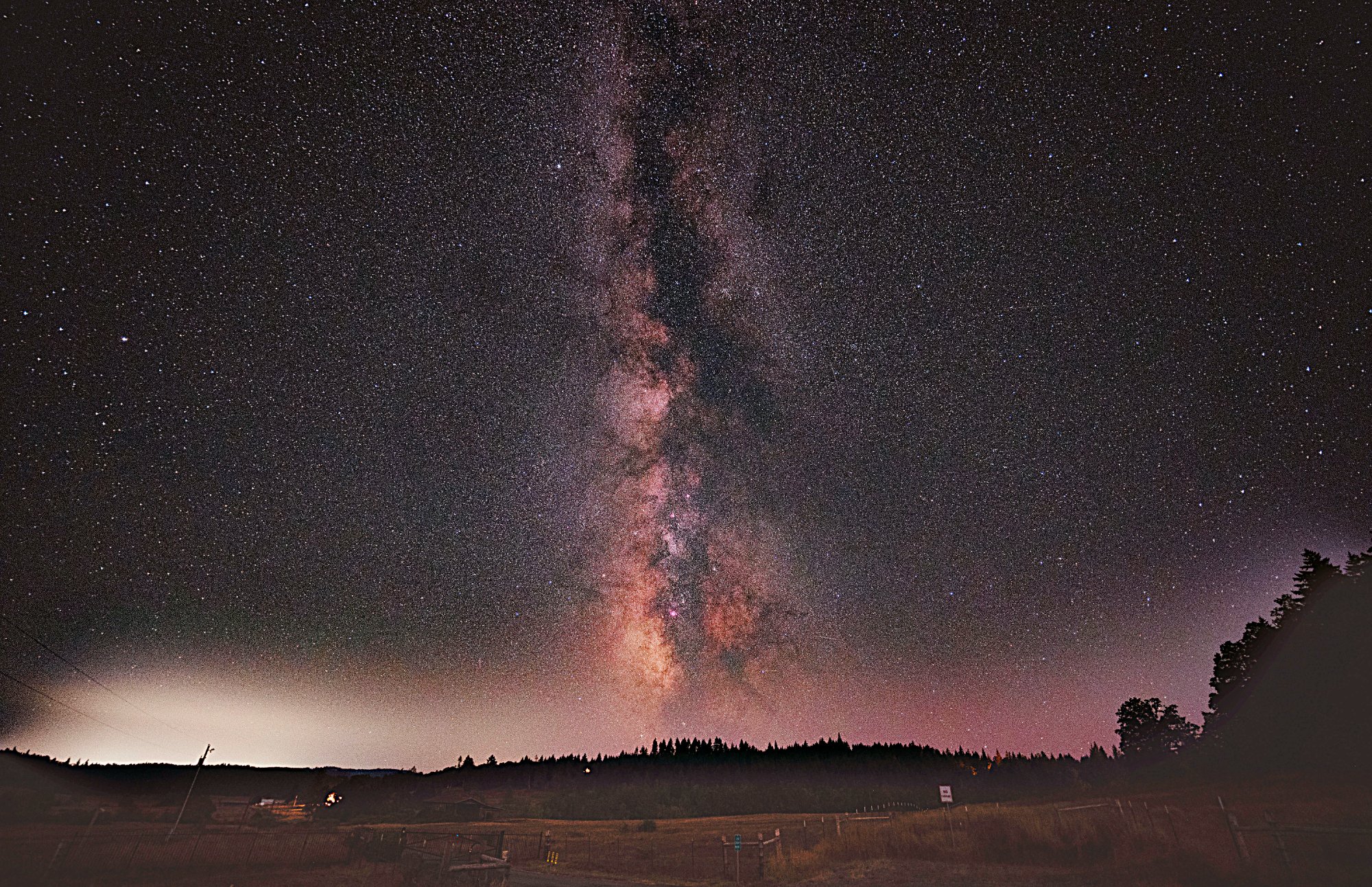 Milky Way rising over Spencer Shadow Ranch with treeline silhouette and ranch fences